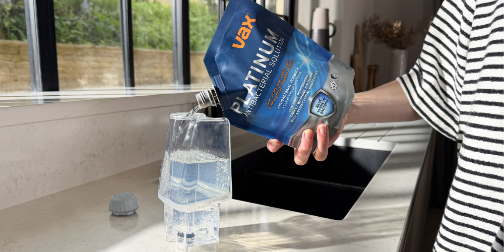 Pouring Vax carpet cleaner solution into a carpet cleaning water receptacle